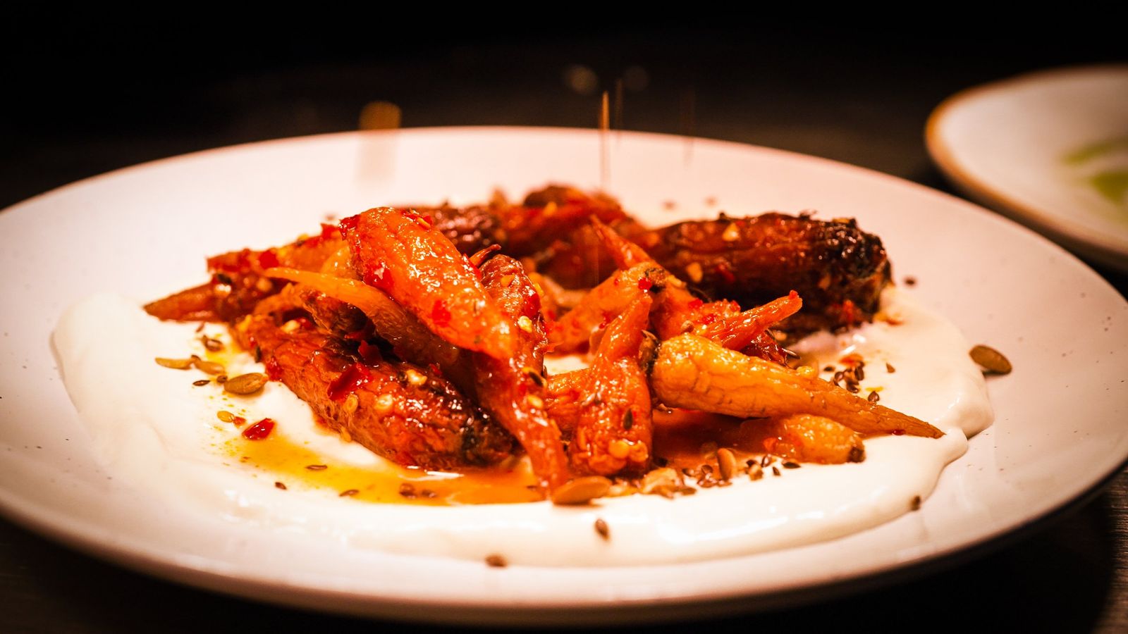 Glazed heritage carrots with chilli and toasted seeds on a smooth white purée